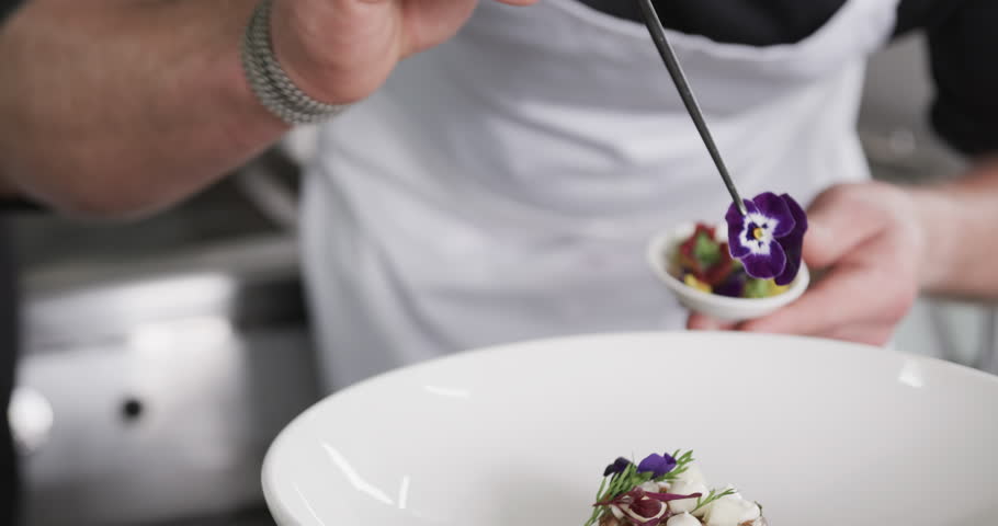 Caucasian male chef decorating meal in kitchen, slow motion. Cooking, profession, food, restaurant and catering, unaltered.