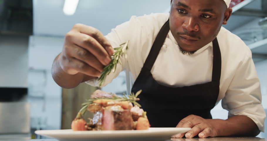 African american male chef decorating meal in kitchen, slow motion. Cooking, profession, food, restaurant and catering, unaltered. Royalty-Free Stock Footage #1109281589