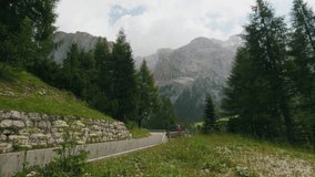 Silver sport car driving on a twisty mountain road in the Italian Dolomites Alps. Amazing view with hills and sky in background, rally scenic route on high altitude for inspiring videos.