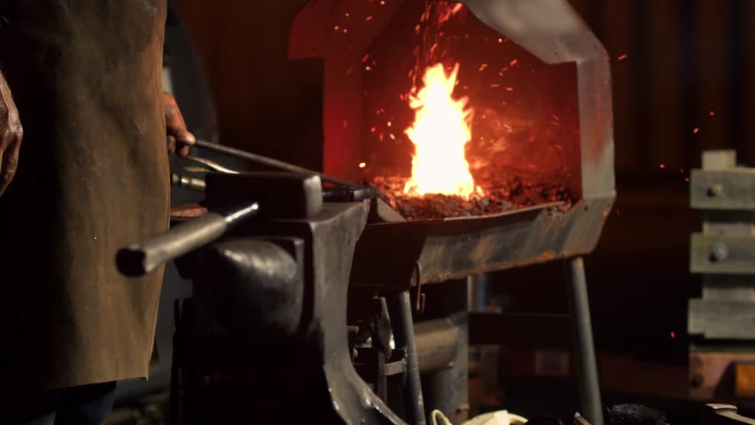 Blacksmith Heats Metal in a Furnace Close-up. Furnace in a Forge with a Fire, Man Heats the Metal Until it Melts so That he Can Hit it with a Hammer on the Anvil.
