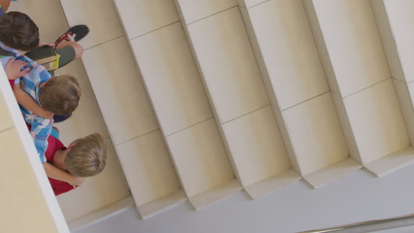 Video of top view of caucasian boys running upstairs at school. primary school education, knowledge and learning concept.