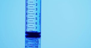 Video of laboratory syringe with copy space on blue background. Science, research and chemistry concept.