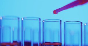 Video of laboratory pipette and test tubes with copy space on blue background. Science, research and chemistry concept.