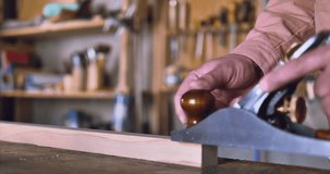 A carpenter in a red jacket with long sleeves works with a hand plane. In move. The video has high-quality sound