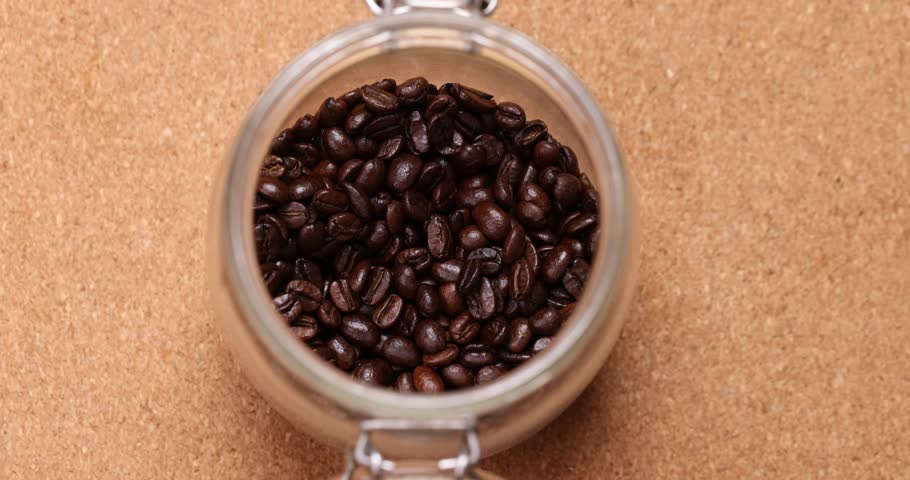 Scoop up Coffee Beans from the jar and focus on th coffee scoop.