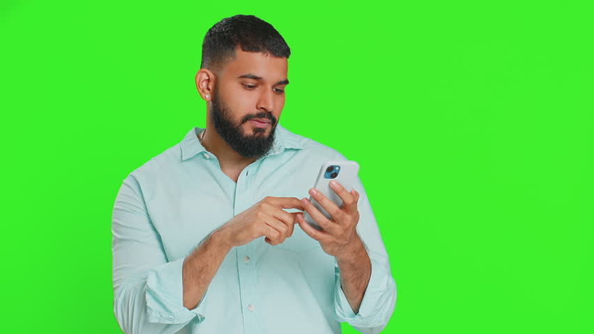 Happy excited Indian young man guy use smartphone typing browsing shouting say wow yes found out great big win good news lottery goal achievement celebrating success, winning play game on chroma key Royalty-Free Stock Footage #1109296357