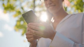 Close-up woman holding phone outdoors in sunlight smiling female businesswoman girl student browsing social network sending sms message checking email on smartphone using mobile application chatting - Powered by Shutterstock - Get 15% off with code: PIKWIZARD15