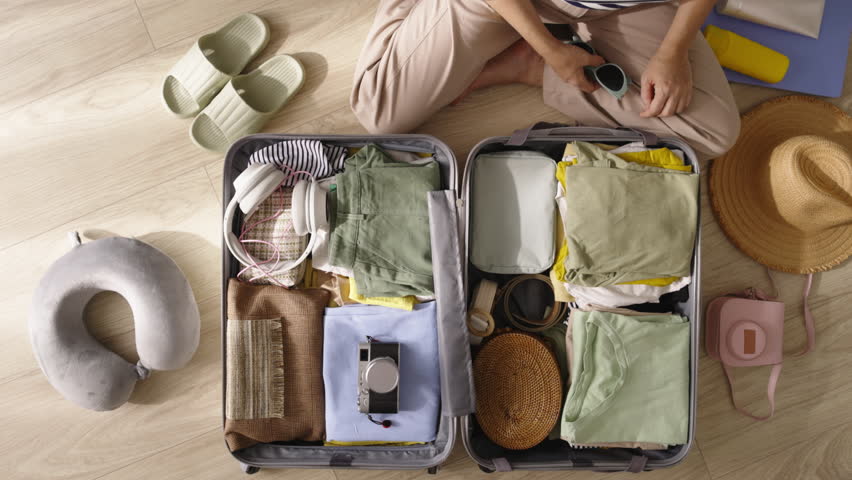 Woman packs bags, goes home from vacation travel trip. Sad unhurried packing of things, clothes home, reluctance to leave from amazing summer vacation weekends back to native lands. Top view.  Royalty-Free Stock Footage #1109311961
