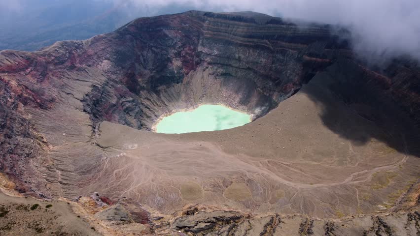 Sunny aerial of deep volcano crater lake as cloud begins to roll in