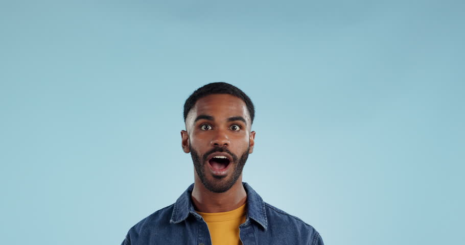 Shocked man, pointing and news announcement with wow in studio, surprise emoji and advertising. Mockup, mexican person and smiling in casual fashion for offer and notification by blue background Royalty-Free Stock Footage #1109314413