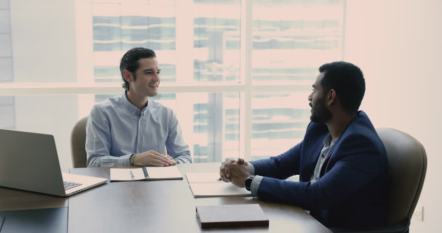 Smiling male entrepreneurs sit at modern office, make deal, shaking hands after finishing meeting. Positive people discussing agreement working together. Teamwork, successful business, job interview Royalty-Free Stock Footage #1109316717
