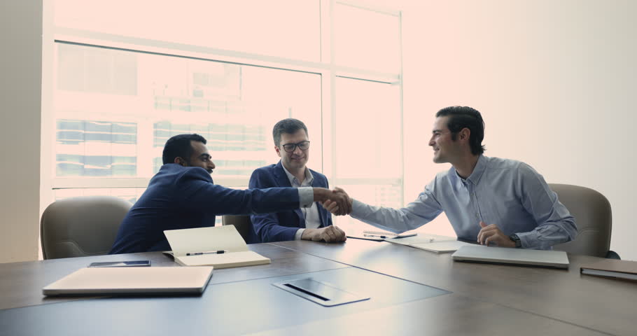 Three multiethnic businesspeople holds negotiation in modern boardroom, conclude partnership agreement handshake, starting joint project, make commercial deal in office, sell and buy company services | Shutterstock HD Video #1109316741