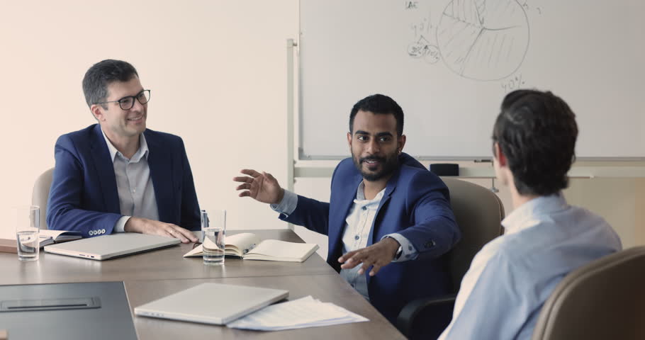 Company management, negotiations of three multiethnic business partners or shareholders. Group of diverse businessmen met in boardroom for briefing, share opinion, ideas seated at desk in board room | Shutterstock HD Video #1109316771
