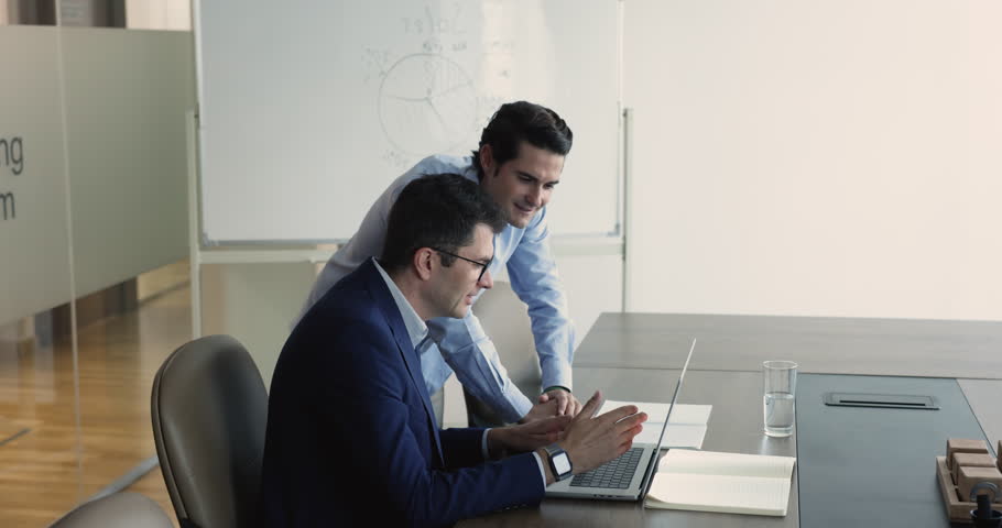 Two businessmen work in office enjoy teamwork, do report together, brainstorm ideas. Colleague explain project to mate, helps with online program usage, learn new application on laptop. Business, team | Shutterstock HD Video #1109318363