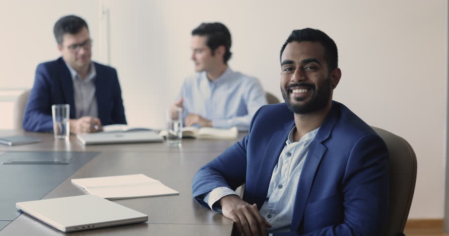 Indian office employee, boss or bank advisor wear elegant suit sit at table with colleagues smiling looking at camera. Leadership, careerism, portrait of successful, skilled professional businessman | Shutterstock HD Video #1109318377