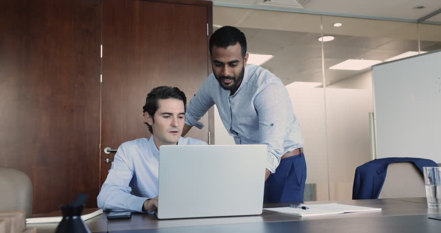 Indian and Hispanic colleagues working in office, check, review sales results, develop marketing strategy, mentor helps to new employee with corporate software, share knowledge, engaged in teamwork | Shutterstock HD Video #1109318379