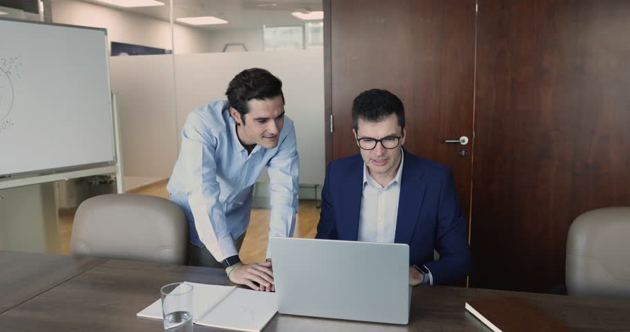 Hispanic and Caucasian colleagues using laptop at meeting in board room, teammate help with new software or program to workmate, share ideas, working on on-line presentation. Apprenticeship, teamwork | Shutterstock HD Video #1109318387