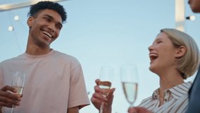 Carefree colleagues enjoying champagne relaxing at summer party closeup. Festive people talking at rooftop. Diverse friends company enjoying alcohol beverages. Corporate event and holiday celebration - Powered by Shutterstock - Get 15% off with code: PIKWIZARD15