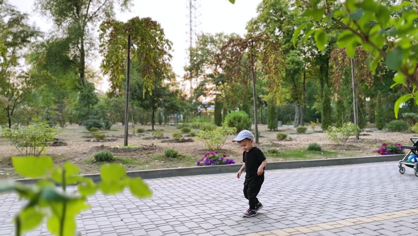 Active playful toddler jumping outdoors. Caucasian baby boy having good time in the park.