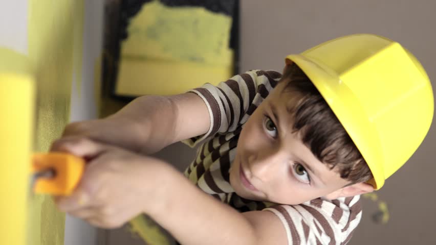 Boy painting wall for yellow paint during home renovation.
