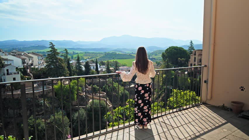 Girl walking to the edge looking in the valley of Ronda mountaintop city, Spain. Tourist woman exploring Puente Nuevo, a stone bridge spanning the old town gorge in Ronda, Andalusia in Europe