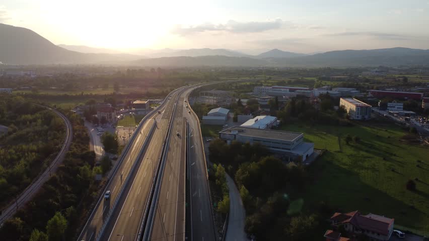 A highway road with traffics ends in sunset landscape.