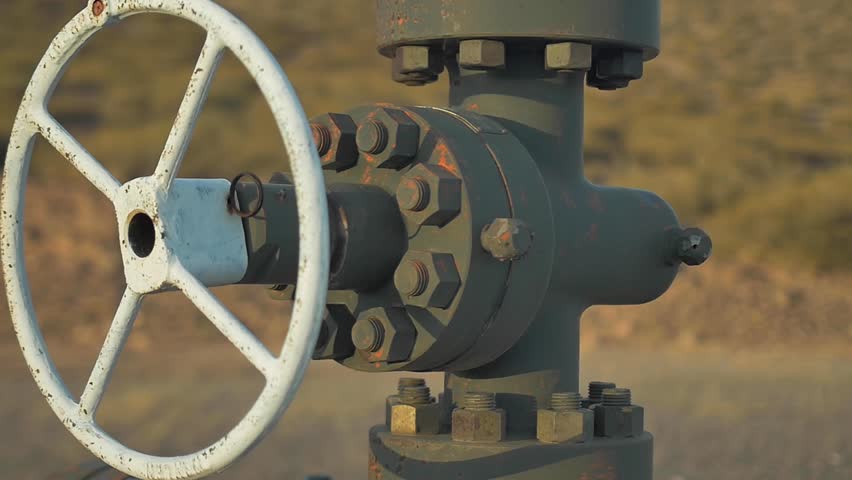 close up on oil valve an piping of abandoned oil well on the desert