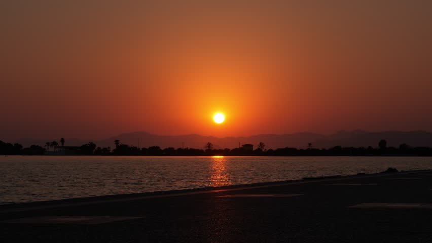 Orange sunset over the waterfront. Beautiful summer sunset over the sea bay.