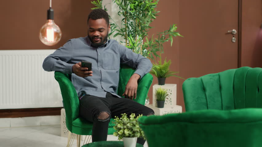 Tourist paying for coffee cup in lobby, using card at pos terminal to buy drink from hotel bar. Traveller thanking employee for serving refreshment in lounge area while he waits. Handheld shot.