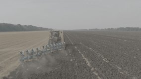 Big red tractor on on rubber tracks, Pulling productive reverse plow on Field. Preparation soil for Planting new crops, of tractor field plowing, Agriculture. Slow motion, 10 bit ungraded D-LOG video.