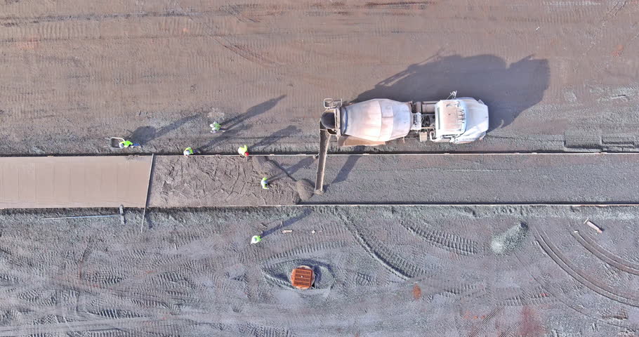 Employees of construction company pour wet concrete on sidewalk footpath new construction project