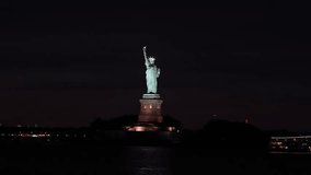 New York by night. 4K night video with Liberty Statue and Manhattan skyline in background. Travel and explore America landmark buildings.
