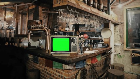 Old TV Green Screen Bar Counter Zoom In Vintage Television. Vintage television with green screen on a bar counter with nobody inside, zoom in Adlı Stok Video