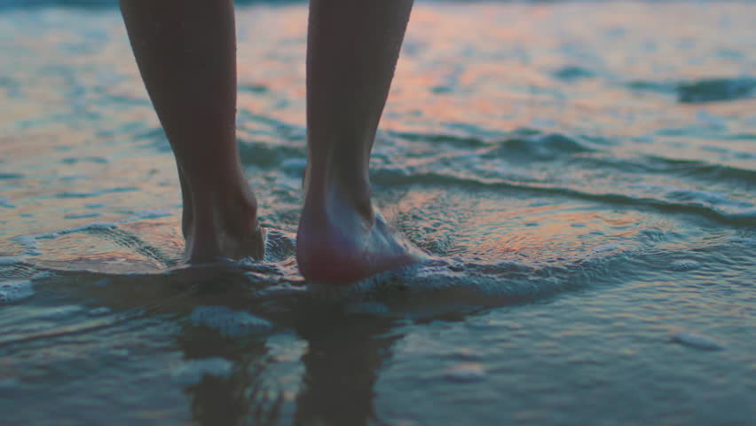 girl walks along the beach during sunset. legs close up. vacation on the seashore.