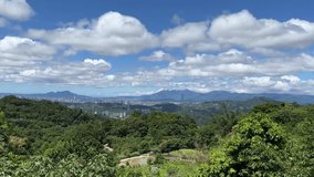 In the video, the entire city of Taipei, Taiwan is overlooked, with blue sky and white clouds flowing rapidly surrounded by mountains.