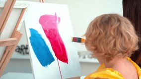 Teacher At Art School Helping Children in Art Class with painting. Woman teaches child to create and work with acrylic paint. Group of primary school kids learning how to draw and color help of their - Powered by Shutterstock - Get 15% off with code: PIKWIZARD15