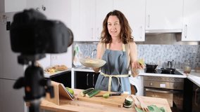adult woman recording herself with the camera while cooking for her healthy food blog
