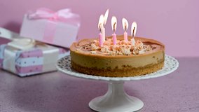 Salted caramel cheesecake with burning candles, gift boxes, pink background - Powered by Shutterstock - Get 15% off with code: PIKWIZARD15