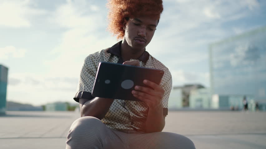 Dark skinned talented digital artist working on creating sketch while inspiring with urban city life. Concentrated African American architect draws on touch pad device for online freelance project
