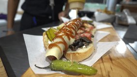 Slow motion shot of a hot dog being covered with sauces and mustard
