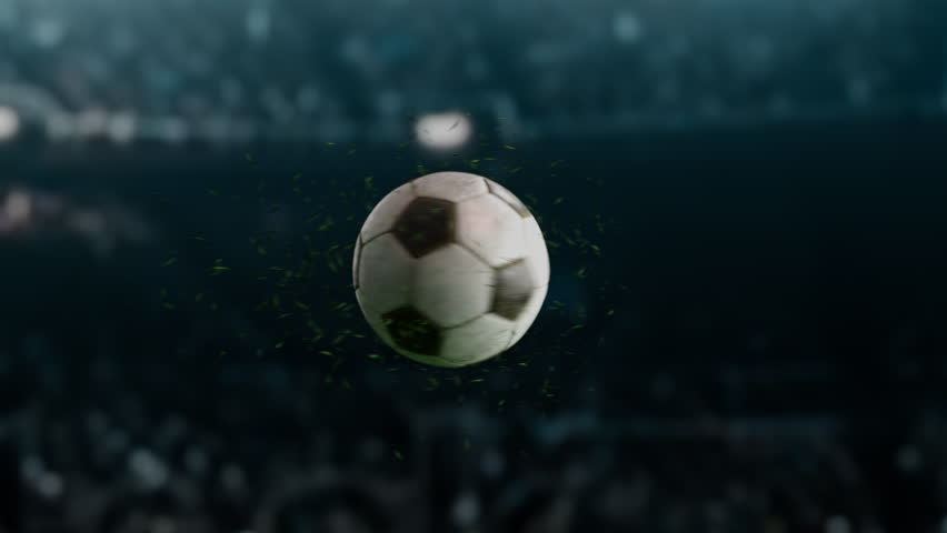A soccer ball floats in the air as grass particles fly around.football ball on a blurry stadium in the background. Royalty-Free Stock Footage #1109369005