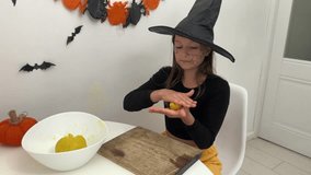 a happy girl in a witch costume makes cookies for Halloween, a child bakes pumpkin-shaped cookies for Halloween - Powered by Shutterstock - Get 15% off with code: PIKWIZARD15