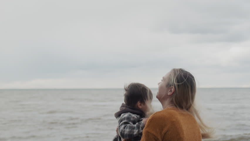 A young mother walks with her son on the shores of the picturesque Lake Ontario