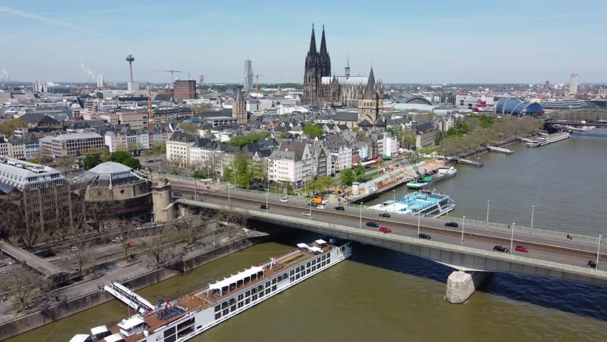 Aerial dolly out of Cologne city center skyline and Cathedral over Cruise ship dock and rush hour traffic on deutzer Bridge. Germany