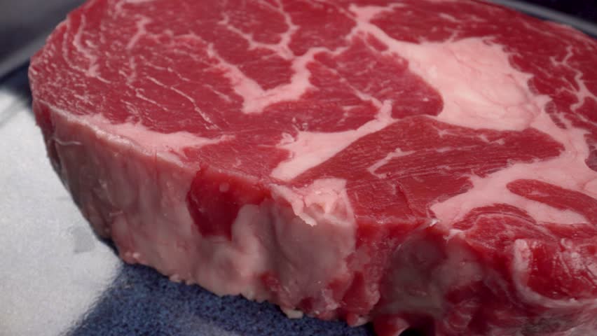 entrecôte ribeye steak close up, rotation, 4k macro view of red meat with fat on blue plate, beef Royalty-Free Stock Footage #1109378237