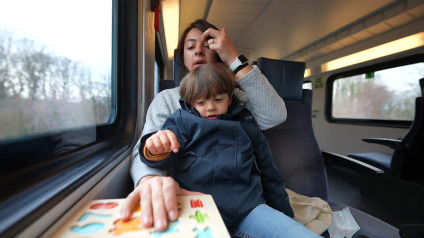 Mother doing school activity with her son while traveling on high-speed train, childhood education concept on the go