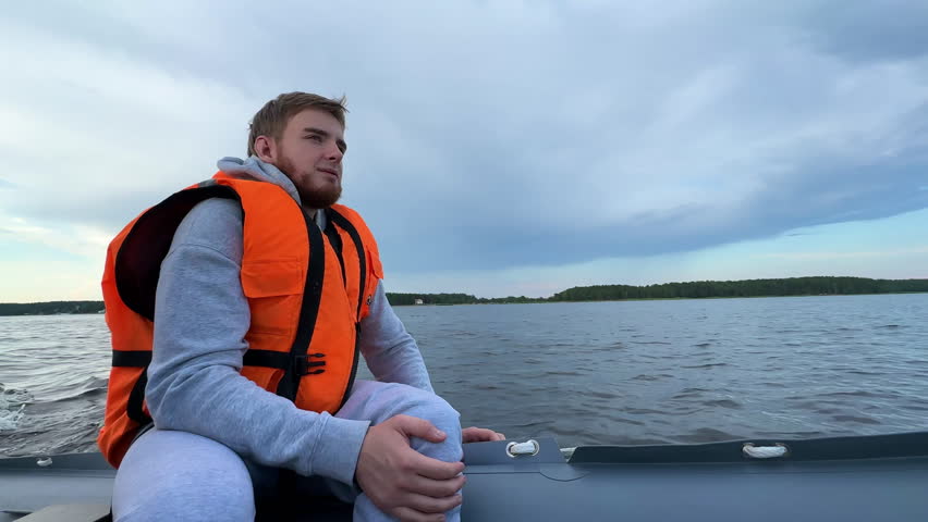 Happy young man traveler in life vest floating in boat on rippling river