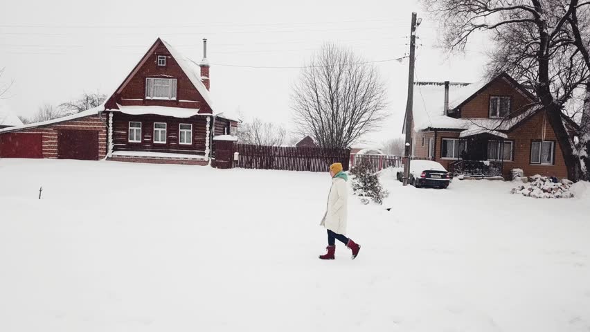 Man in yellow hat walking birch wood old wooden green brown houses winter snowfall cold frozen weather village. Flying suburban area country lifestyle countryside concept. Nature rural suburban 4k 3