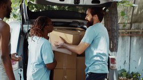 Male and female volunteers at the car giving charity boxes to poor needy and homeless people at community center. At food drive, the less privileged receive donations from a non-profit organization. - Powered by Shutterstock - Get 15% off with code: PIKWIZARD15