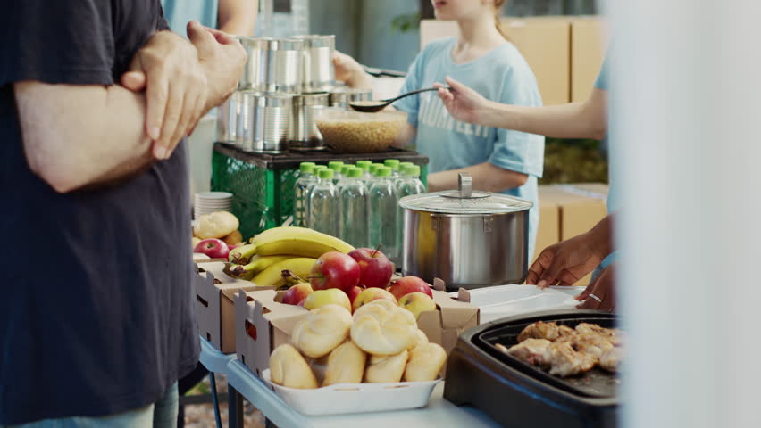 Multiracial team that fights hunger distributes free meals to the poor while helping and supporting the homeless. Warm meals are provided by volunteers in effort to combat hunger and poverty. Royalty-Free Stock Footage #1109388231